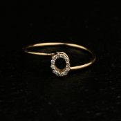 A vintage yellow metal ladies open circle ring having a thin offset band and a central cartouche