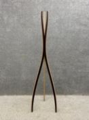 A contemporary plywood coat stand of curvilinear form with raw and black faceted sides on a tapering