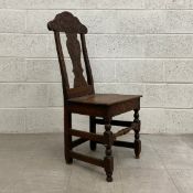 An 18th century oak hall chair having a shaped and hand carved top, splat and side rails over a