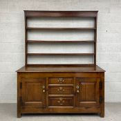 An 18th century oak Welsh dresser with open plate rack above base fitted with three graduating