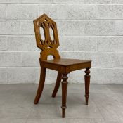 A 19th century oak hall chair with a neo gothic carved back above panel seat on tapering supports.