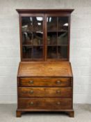 A Georgian mahogany bureau bookcase having a moulded cornice above two glazed cabinet doors and