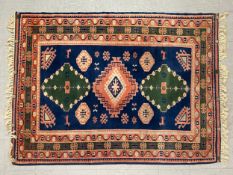 A hand knotted Shirvan carpet with central lozenge medallions on a sapphire ground within stylised