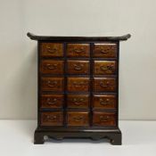 An early 20th century Chinese brass mounted hardwood apothecary chest having a shaped rectangular