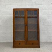 An early 20th century oak floor standing bookcase with glazed doors above two short base drawers.