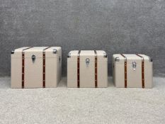 A set of three contemporary beige calico upholstered and mahogany and metal clad graduating travel