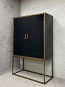 A contemporary cabinet on stand having two polished black mirror finish doors in a brushed brass