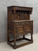 A 17th century style oak dwarf court cupboard having a rectangular top and overhanging carved frieze