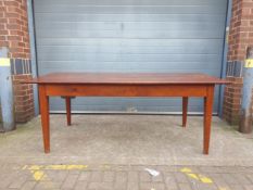 A large fruitwood refectory style dining table having a rectangular plank top raised on four