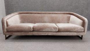 A contemporary three seater sofa having a curved tub style back and arms over a deep cushioned