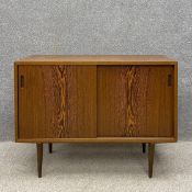 A mid century Danish rosewood sideboard having a rectangular top over two sliding book matched
