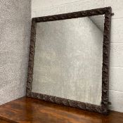 A C.1900 mirror having a square plate in an intricately carved hardwood frame with grape and vine
