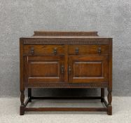 An early 20th century oak side cabinet having a carved gallery back on a thumb moulded top over an
