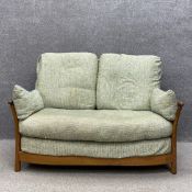 An Ercol Renaissance pattern elm framed two seater sofa having a curved top rail with a slatted