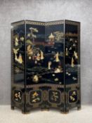 A large 20th century Chinese black lacquered screen comprising four hinged folding panels inset with