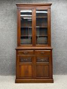 A Victorian walnut library bookcase in two parts with a moulded cornice above two glazed doors,