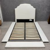 A contemporary double bed upholstered in an oat linen having a tall shaped headboard over a simple