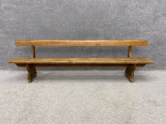 An early 20th century pine tram or train station bench having a long plank top rail and seat