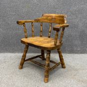 An elm bow smoker's armchair having a curved and scrolled top rail and arms on eight turned spindles