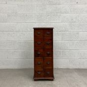 A 20th century teak bank of drawers having a square thumb moulded top over and arrangement of ten
