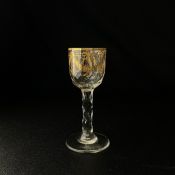 An 18th century Georgian wine glass having a gilt cup raised on a facet cut stem on a circular base.