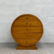 A contemporary teak chest of drawers of circular barrel form with five shaped drawers raised on a
