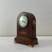 A 19th century mahogany mantle clock having an arched top with an enamelled dial over an inlaid