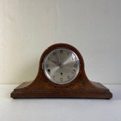 A 20th century marquetry inlaid mahogany mantle clock of arched form with a silvered dial bearing