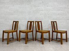A set of four mid 20th century oak dining chairs each having a square open back with shaped and