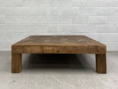 A large contemporary low pine coffee table having a square parquetry top raised on four heavy square