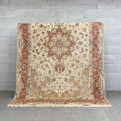 A large signed silk Persian Tabriz carpet having a single central medallion in pale reds, greens and