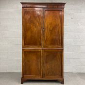 A 19th century flame mahogany wardrobe fitted with panel doors enclosing hanging rail on shaped