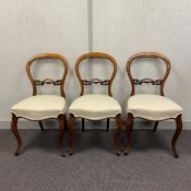 A set of three Victorian walnut balloon back side chairs each having a shaped open back with a