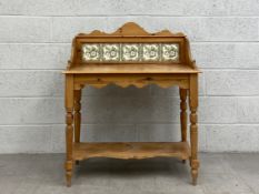 A C.1900 pine washstand having a tiled gallery back in a shaped frame on a moulded plank top with
