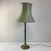 A simulated brass table lamp having a narrow stem with fluted collars raised on a circular plinth
