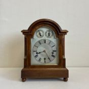 A 19th century mahogany mantle clock having an arched and moulded pediment over single glazed door