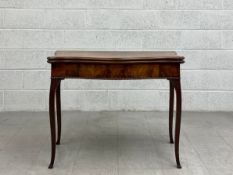 A Georgian mahogany card table having a fold over baize lined quatrefoil top over a carved