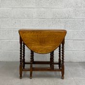An early 20th century oak drop-leaf table having an oval thumb moulded top raised on six stretchered