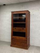 A contemporary hardwood bookcase having a single glazed door opening on to an interior with an