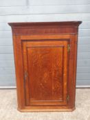 A Georgian oak wall mounted corner cabinet having a beadwork moulded cornice with a crossbanded