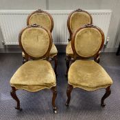 A set of four Victorian walnut balloon back dining chairs each having a scrolling cresting carved