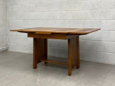 A mid 20th century oak extending dining table having a square top with two slide leaves raised on