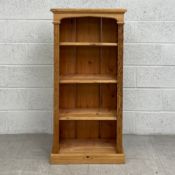 A 20th century pine open bookshelf having a moulded cornice with shaped pediment over four shelves