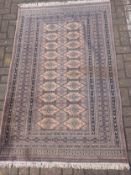A Bokhara carpet having two rows of ten rose pink diamond lozenges over a lilac ground within