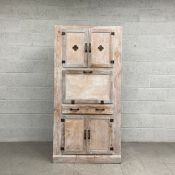A mid-century limewashed and distressed pine pantry cabinet having a pair of cupboard doors with