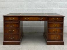 A 20th century mahogany twin pedestal desk having a rectangular tooled and gilt green leather top