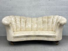 A C.1900 butterfly sofa having a curved and ribbed back and arms upholstered in a cream damask
