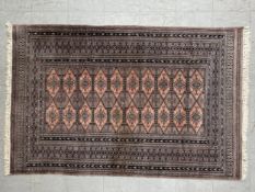 A hand knotted Bokhara rug with twelve pale red diamond lozenge medallions within mutiple