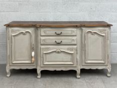A painted oak breakfront sideboard in the 19th century French provincial style having a shaped