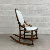 A Victorian walnut balloon back rocking chair having a carved cresting and shaped arms with a